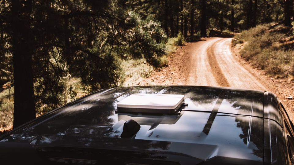 Starlink Mini held in the Veritas Mini Mount on the roof of a truck parked on a forest road