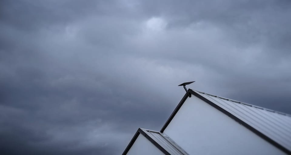 Starlink V5 dish mounted on a roof beneath storm clouds